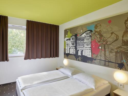 トリーアにあるB&B Hotel Trierのベッドルーム1室(ベッド1台付)が備わります。壁には絵画が飾られています。