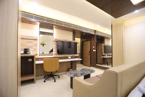 a room with a desk and a chair and a tv at Kings Bury Inn in Kumbakonam