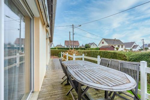 Una terraza de madera con una mesa en un balcón. en La Maresquerie, en Grandcamp-Maisy