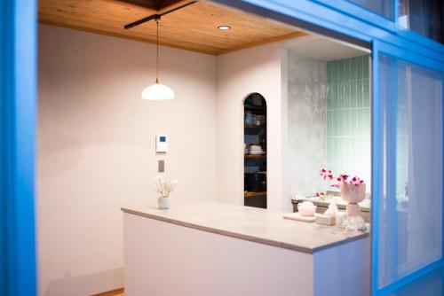 a kitchen with white walls and a counter with flowers at はなれ奏HanareSou-天然温泉付き貸別荘-1棟貸し in Kirishima