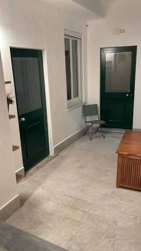 a room with two green doors and a chair at Al Castello 1 in Riomaggiore