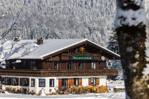 a large wooden building with a snow covered mountain at Wassererlehen in Bischofswiesen