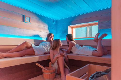 three women sitting on a bench in a sauna at Villa Cecha B&b &Wellness in Ostend