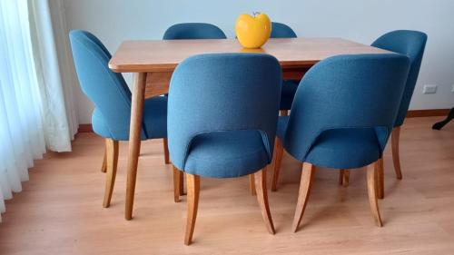 a dining room table with blue chairs and a vase on it at Bello apartamento en Jesús María! in Lima