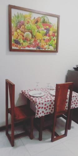 Chef Naturelle's Guest House في كاندي: طاولة مع كرسيين و لوحة على الحائط