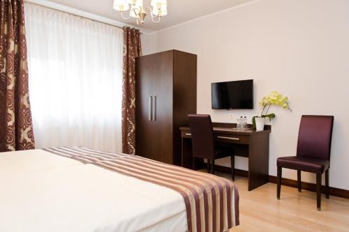 a bedroom with a bed and a desk with a television at Pokoje De Luxe Figaro in Płock