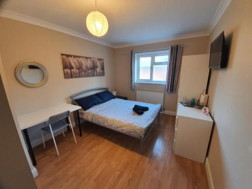 a bedroom with a bed and a desk and a table at Ilford Rooms in Goodmayes