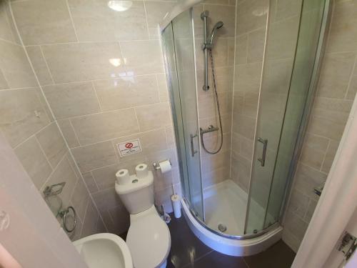 uma casa de banho com um WC e uma cabina de duche em vidro. em Ilford Rooms em Goodmayes