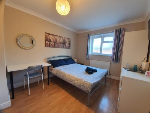 a bedroom with a bed and a desk and a window at Ilford Rooms in Goodmayes