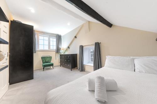 um quarto com uma cama branca e uma cadeira verde em Town centre property convenient for the fells em Keswick