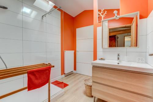 uma casa de banho com paredes cor de laranja, um lavatório e um chuveiro em La Fourragère - Maison pour 5 