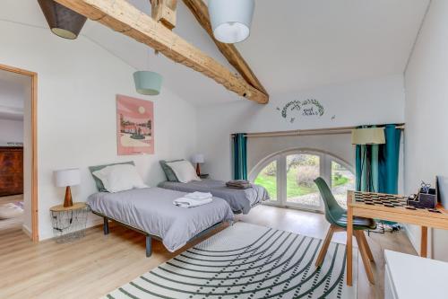 a bedroom with two beds and a table and a desk at La Fourragère - Maison pour 5 