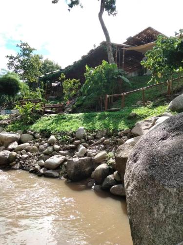 a river with rocks in front of a house at Lhong Chiang Dao Glamping หลงเชียงดาว in Chiang Dao