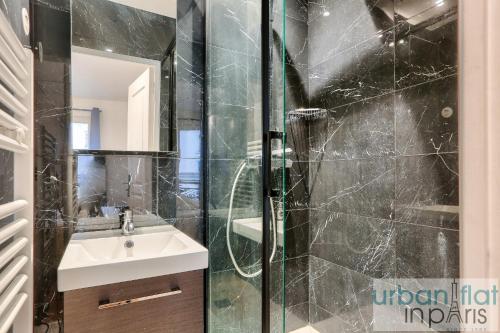 uma casa de banho com um chuveiro, um lavatório e um espelho. em Urban Flat 103 - Spacious Flat near Grands Boulevards em Paris