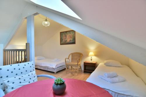 een zolderkamer met 2 bedden en een tafel bij Les Pieds dans le Sable - Appt vue mer in Saint-Cast-le-Guildo