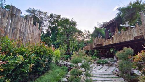 a garden with a wooden fence and a stone path at Lhong Chiang Dao Glamping หลงเชียงดาว in Chiang Dao