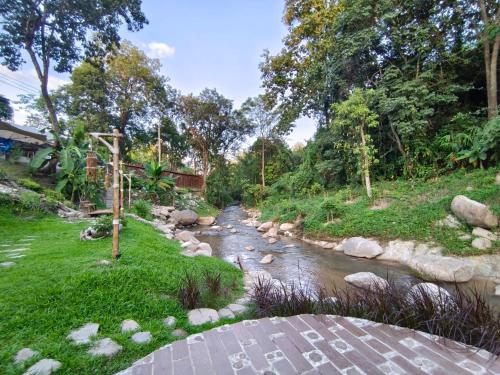 a river with rocks in a yard with trees at Lhong Chiang Dao Glamping หลงเชียงดาว in Chiang Dao