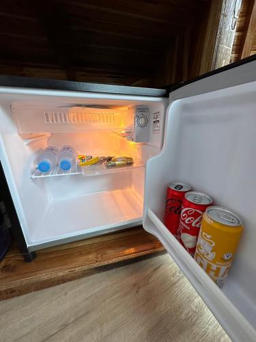an open refrigerator with drinks and cans of soda at Lhong Chiang Dao Glamping หลงเชียงดาว in Chiang Dao