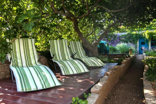 a row of green and white chairs sitting under trees at Holiday Home ART - Bol in Bol