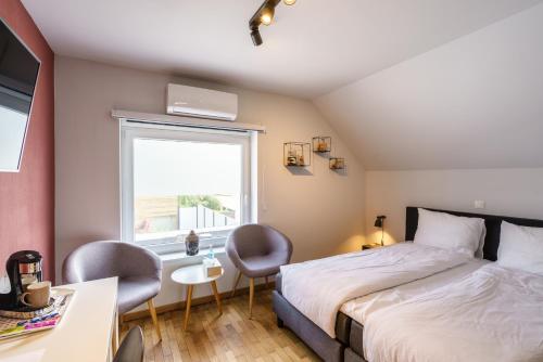 a bedroom with a bed and two chairs and a window at Villa Cecha B&b &Wellness in Ostend
