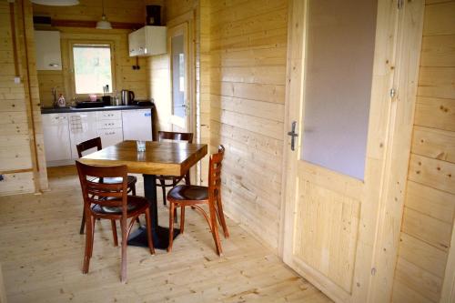 a kitchen with a wooden table and chairs at Camping Szczecinek Domy Wypoczynkowe in Szczecinek