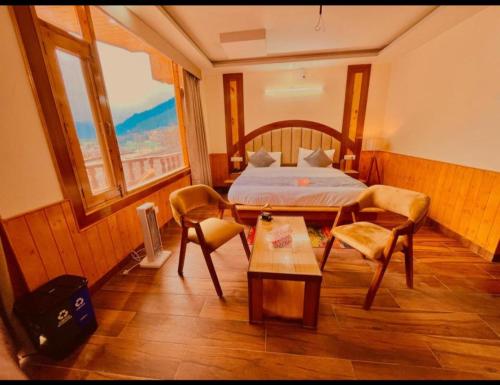 Hotel Lee Green- best family hotel in Darjeeling في دارجيلنغ: غرفة نوم بسرير وطاولة وكراسي