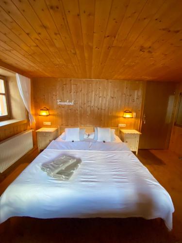 a large white bed in a room with a wooden ceiling at Älpler Stuba Appartements am Lärchenhof in Warth am Arlberg