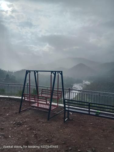 un columpio sentado en la cima de una colina con vistas al agua en Mistymout Homestay, en Attappādi