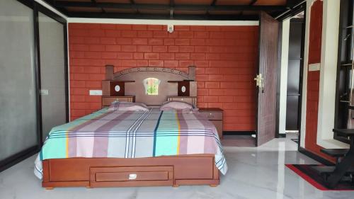 Cama en habitación con pared de ladrillo rojo en Mistymout Homestay, en Attappādi