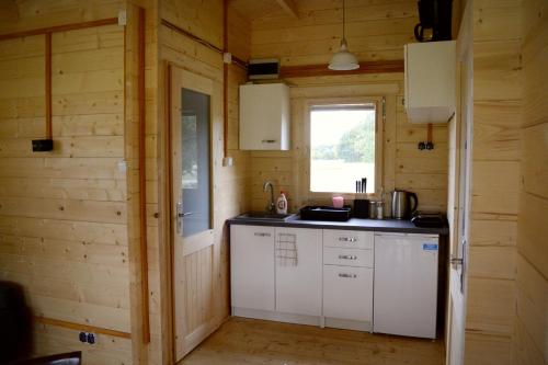 a kitchen with white cabinets and a window at Camping Szczecinek Domy Wypoczynkowe in Szczecinek