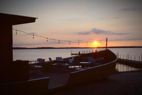 a group of tables and chairs on a dock with the sunset at Camping Szczecinek Domy Wypoczynkowe in Szczecinek