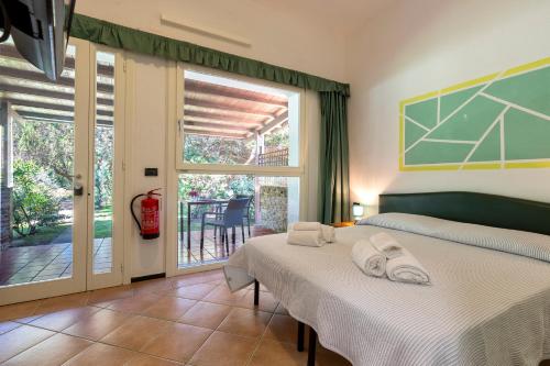 two beds in a bedroom with a view of a patio at Residence Le Vele in Stintino