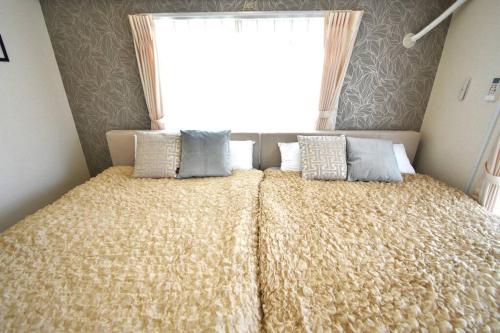 a bedroom with a bed with pillows and a window at ゆったり1LDKで最大8人まで宿泊可能！博多駅・キャナルも徒歩圏内！コンビニ・スーパー徒歩１分！ in Sumiyoshi