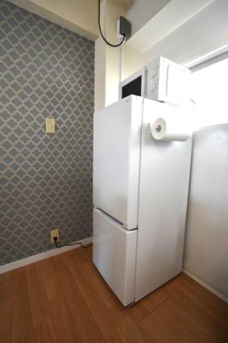 a kitchen with a white refrigerator in a room at ゆったり1LDKで最大8人まで宿泊可能！博多駅・キャナルも徒歩圏内！コンビニ・スーパー徒歩１分！ in Sumiyoshi