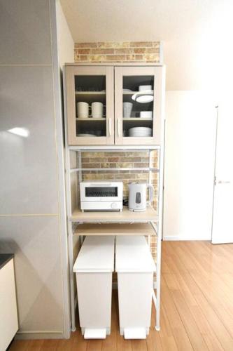 a kitchen with a white shelf with a microwave at ゆったり1LDKで最大8人まで宿泊可能！博多駅・キャナルも徒歩圏内！コンビニ・スーパー徒歩１分！ in Sumiyoshi