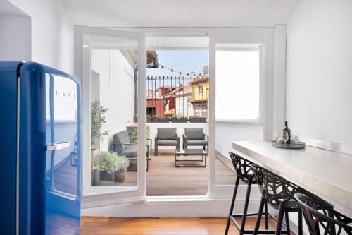 een keuken met een deur naar een balkon met stoelen bij Historical Penthouse at Cardosas Block in Porto