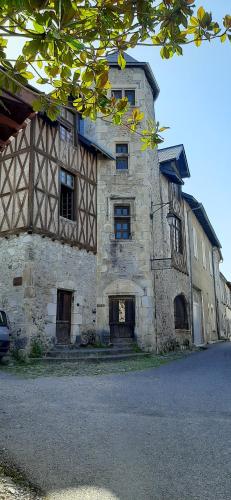un vecchio edificio in pietra con un'auto parcheggiata di fronte di Hôtel Candide a Saint-Bertrand-de-Comminges