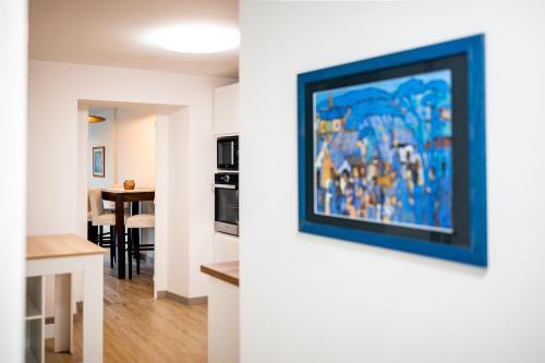 a living room and kitchen with a painting on the wall at Les Létruns - Appart - 4 pers - Vue sur la mer in Saint Malo