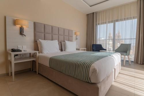 Cette chambre comprend un grand lit et une fenêtre. dans l'établissement Maritim Antonine Hotel & Spa, à Mellieħa