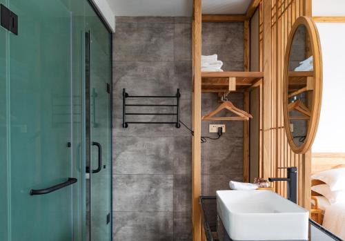 a bathroom with a sink and a glass shower at Zhangjiajie Qiquan Vacation B&B in Zhangjiajie