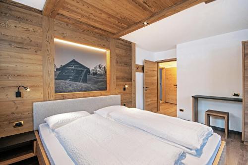 ein Schlafzimmer mit einem Bett in einem Zimmer mit Holzwänden in der Unterkunft Tinahof in Wolkenstein in Gröden