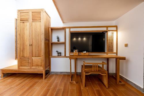 a room with a desk and a tv and a cabinet at Zhangjiajie Qiquan Vacation B&B in Zhangjiajie