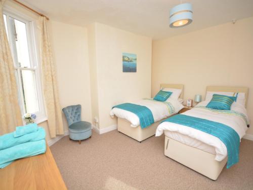 1 dormitorio con 2 camas y 1 silla en 2 Bed in Bideford 37262 en Bideford