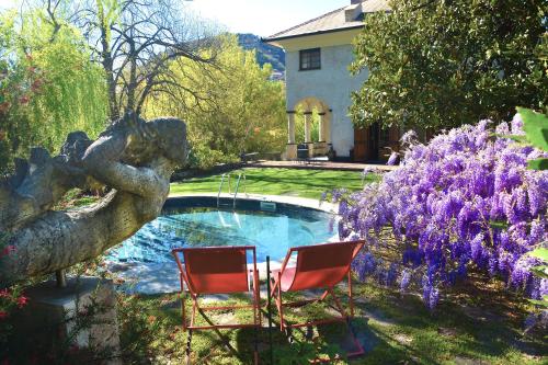 duas cadeiras e uma piscina num quintal com flores roxas em Relais Rantegosa - Holiday home em Chiavari