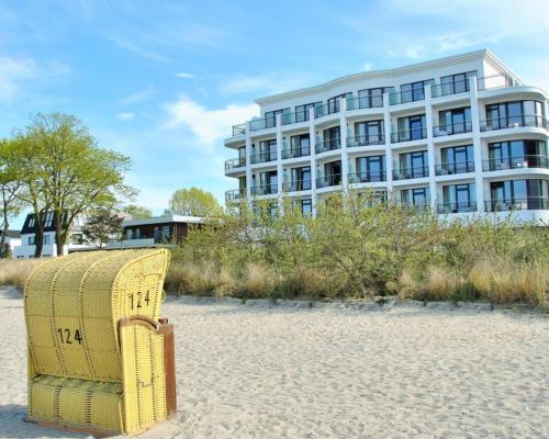 a yellow wicker chair sitting on the beach in front of a building at SeeHuus Lifestyle Hotel in Timmendorfer Strand