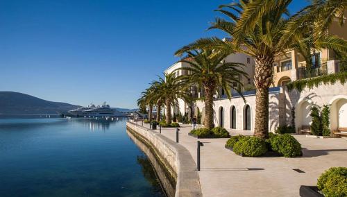 a building with palm trees next to a body of water at M&M apartments in Tivat