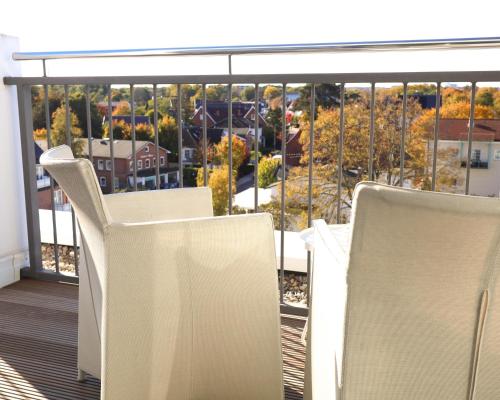 a balcony with two white chairs and a view of trees at SeeHuus Lifestyle Hotel in Timmendorfer Strand