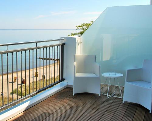 a balcony with a table and chairs and the ocean at SeeHuus Lifestyle Hotel in Timmendorfer Strand