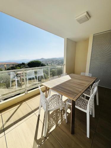 d'une table et de chaises en bois sur un balcon avec vue. dans l'établissement Bel appartement neuf vue mer, à LʼÎle-Rousse