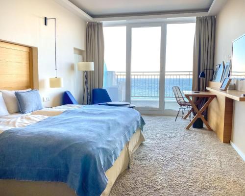 um quarto de hotel com uma cama, uma secretária e janelas em SeeHuus Lifestyle Hotel em Timmendorfer Strand